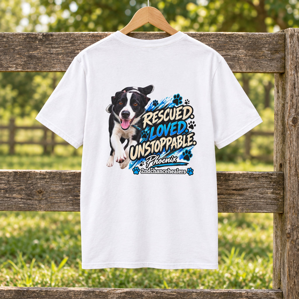 A white short-sleeve crewneck t-shirt featuring a colorful graphic print on the front. The graphic shows a black and white dog with sunglasses, surrounded by blue paw prints and the text 'RESCUED.